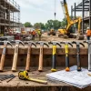 Professional claw hammers arranged on a construction workbench with industrial tools and building materials.